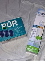 Box of Pur Plus replacement water filters, showing three dark blue cartridges and text indicating lead reduction and great taste.