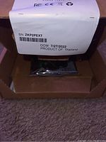 View of the Seagate Barracuda hard drive box showing product label with serial number, manufacturing date (7/27/2022), and origin (Product of Thailand). Drive is visible inside anti-static bag through open flap of box.