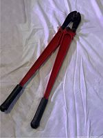 Full view of the red-handled bolt cutters with black rubber grips on the handles, showing overall condition and size.