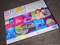 Front box view of 4M Steam Powered Kids Crystal Science Kit, colorful with sample crystals and children shown.