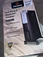 Photo of boxed Pelonis oil-filled radiant heater showing front label with product features and image of heater.