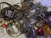 Photo showing tangled assortment of mixed metal chains, bangles, and various jewelry pieces with some colored accents and enamel detailing