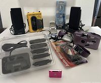 Full lot showing all electronic devices including speakers, iPod Shuffle, fitness tracker, camera, and accessories