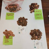 Photo showing piles of Canadian pennies separated by decades 1970s, 1980s, 1990s and a pile of commemorative pennies from 1952 to 2002, with labels for each group on a white surface.