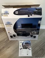 Full unopened box of Enigma 600X surround sound system showing branding and contents image.