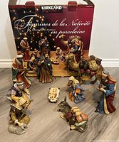 The full set of 10 nativity porcelain figurines displayed in front of the original box showing packaging and branding.