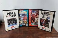 Four Sega Genesis game cases including NHL 95, LA Russa Baseball 95, NFL Football 94, and Street Fighter Special Champion Edition shown standing on a surface.