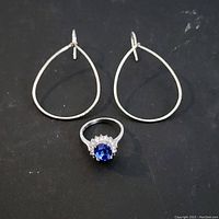 Full set of sterling silver jewelry including the ring with blue sapphire and rhinestones, and the pair of teardrop shaped hooked earrings.