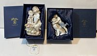Two vintage Adeline porcelain figurines in original blue boxes with satin lining, showing boy hugging dog and seated girl with dog with flowered base.