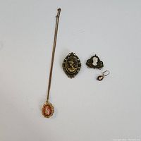 Full view of the four cameo jewelry items: necklace with pendant, brooch, smaller pendant, and earring.