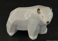 Side angle showing full body of porcelain polar bear with gold tone ears, nose, eyes, and tail.