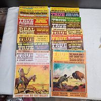 Photo showing a stack of 13 True Frontier vintage Western magazines with multi-colored illustrated covers and prominent text headlines.