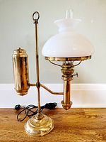 Antique electrified brass student oil lamp with white milk glass shade shown from the front right side.
