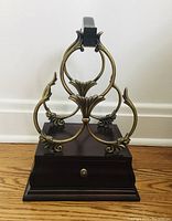 Front view of the wine rack showing the metal loops for holding three bottles and the small drawer on the wood base.