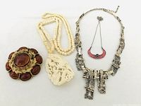 Full view of the lot on white background showing all jewelry items including the brooch and three necklaces.