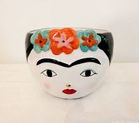 Front view of the ceramic planter showing the painted face of Frida Kahlo with flowers on the head.