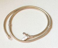 Close up of the coiled sterling silver snake chain showing the smooth texture and lobster clasp with Pandora tag.