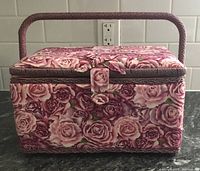 Front view of sewing box showing pink and purple fabric rose exterior and woven handle