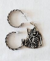 Two twisted sterling silver hoop earrings with post backs and clear plastic backings displayed alongside a Gothic-style Grim Reaper pendant made of 925 silver showing frontal detail.