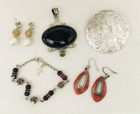 Five-piece jewelry set including pendant, brooch, two pairs of earrings, and bracelet shown together from overhead.