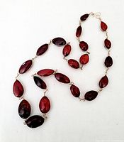 Photo of vintage amber bead necklace arranged on white background to show shape and size of individual beads, highlighting the wire wrapped links and gold hook clasp.