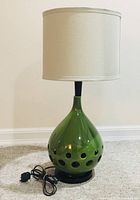 Full view of the lamp with shade and cord on carpeted floor