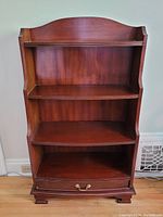Front view of the wooden shelving unit showing three shelves and a drawer at the bottom.