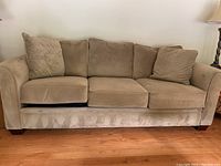 Front view of plush tan three-seater sofa with cushion detail