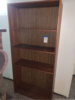 Front view of four shelf wooden bookcase with wood grain back panel