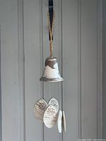 Front view of cream and brown ceramic bell-shaped wind chime with leaf-etched oval ceramic chimes hanging beneath