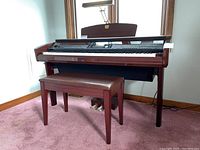 Full view of the Yamaha Clavinova digital piano with bench and lamp