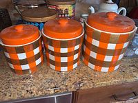 Set of three ceramic canisters with plaid pattern sitting on a kitchen counter