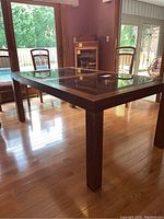 Angle view of rectangular Drexel glass inset dining table with dark wooden frame and legs on hardwood floor.