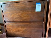 Front view of the solid wood 2 drawer lateral file cabinet showing wood grain and a note with lot information attached.