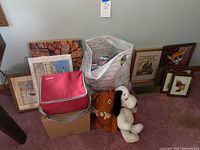 Overview photo showing multiple framed prints, CD carrying case, stuffed animals, and crocheting bag on carpet floor.