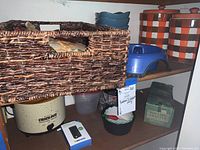 Shelf showing Rival crockpot, portable power stick, basket, pet bowl and Rubbermaid containers along with the Italian ceramic jars on upper shelf