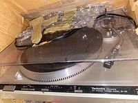 Photo of vintage Technics turntable with plastic dust cover inside a cardboard box with bubble wrap.