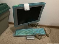 Apple Studio Display with matching translucent keyboard and wired adapter box on carpet floor.
