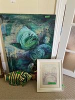 Original painting on wood with large green fish and two decorative fish sculptures near floor, print in frame leaning on floor