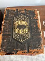 Photo of the worn, detached front cover with embossed gold lettering 'Holy Bible' and heavy surface wear.