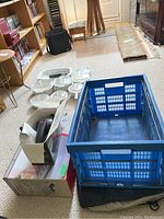 Photo of blue plastic crate, plastic food storage containers on floor, and boxed electric pump for air mattress.