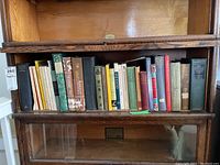 Photo of wooden bookshelf with various classic books including travel and history, some with faded or worn covers.