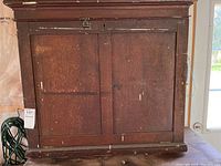 Wood cabinet with closed front panel showing surface scratches and paint marks