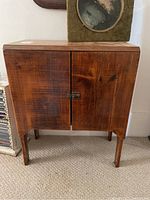 Front view of the wooden cabinet showing two doors with wood grain and metal latch.