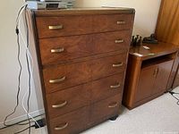 Front and angled view showing the medium brown wood finish and brass-colored handles on five drawers.