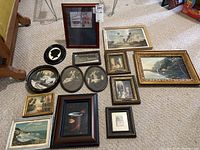 Overview of all 12 framed prints and paintings arranged on floor showing variety of styles and sizes