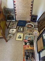 View of lot items arranged on floor including framed prints, plates, magazines, and tins with royal themes.