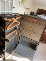 Outer and inner view of vintage travel trunk showing wood hangers, drawers, and drop-down compartment