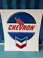 Close up photo of a large Chevron decal on white backing, showing condition and scale.
