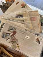 Close-up photo of aerograms and stamp sheets showing various bird designs and commemorative stamps.